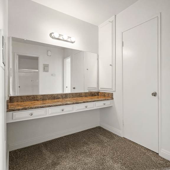 a white bathroom with a vanity and a mirror.