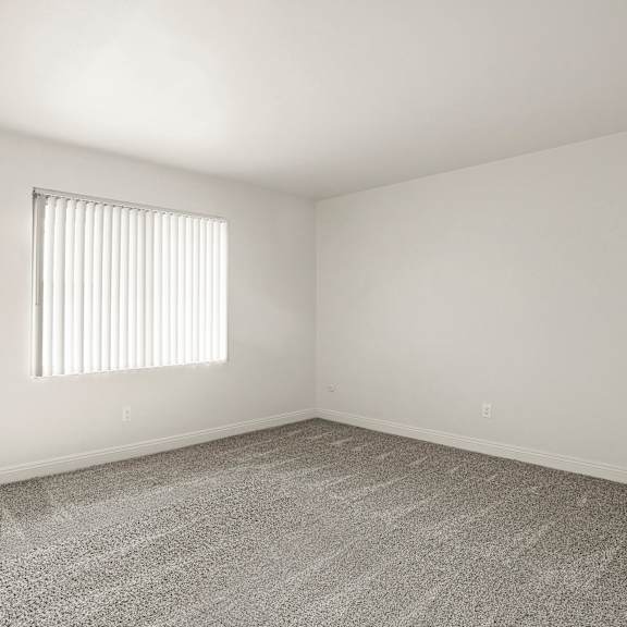 a room with a carpeted floor and a window with blinds.