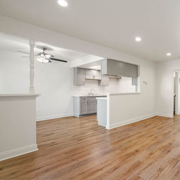 a spacious room with wooden flooring and a ceiling fan.