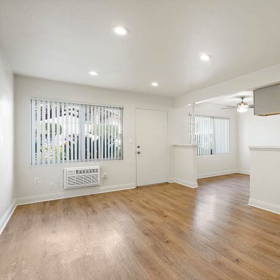 a spacious room with wooden floors and white walls.