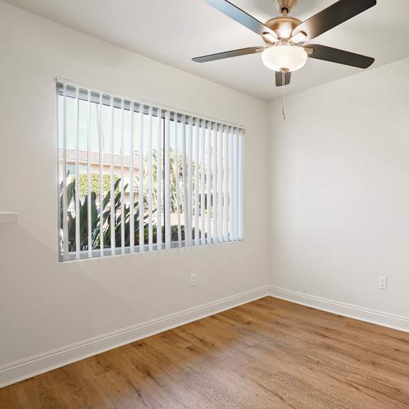 a room with a ceiling fan and a window with blinds.