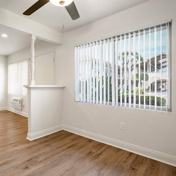 a room with a window covered by white blinds and a ceiling fan.