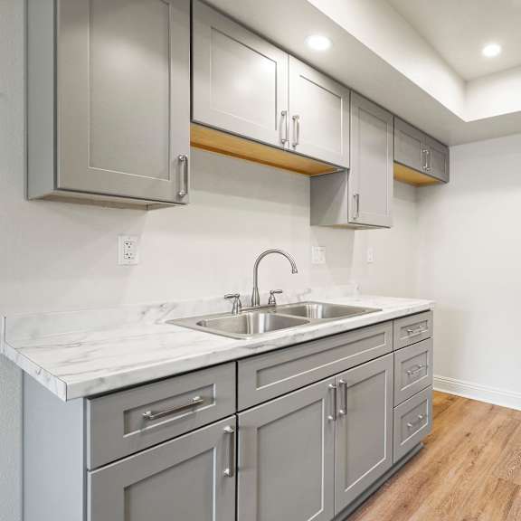 a kitchen with a marble countertop and grey cabinets.