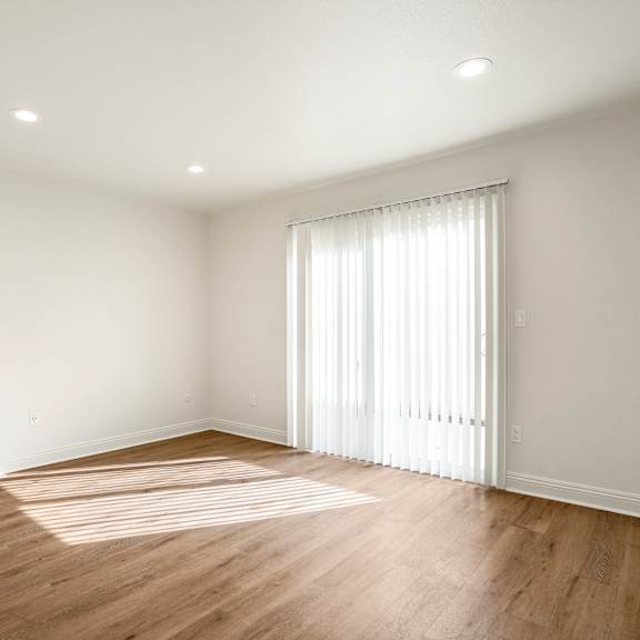 a room with wooden floors and a window with white curtains.