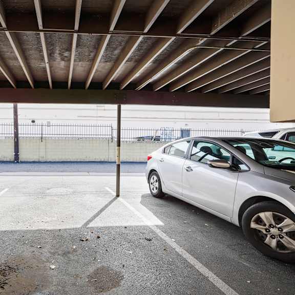 a white car is parked in a parking lot under a covered area.