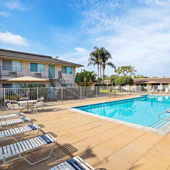 a pool surrounded by chairs and a fence.