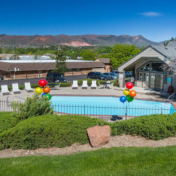 a pool surrounded by a hedge and balloons.