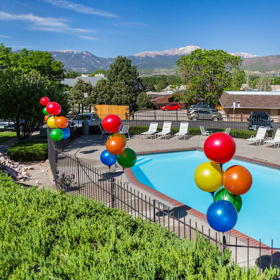 a pool surrounded by trees and balloons.