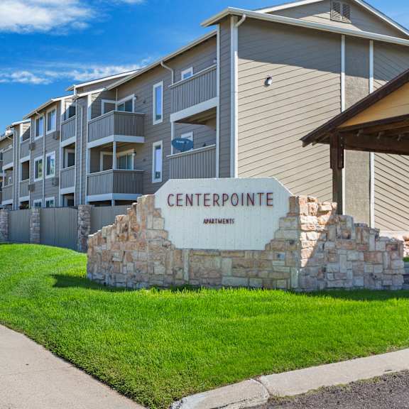 a stone sign that says centerpointe apartments sits in front of a building.