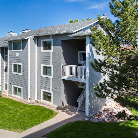 a grey apartment building with a green lawn in front.