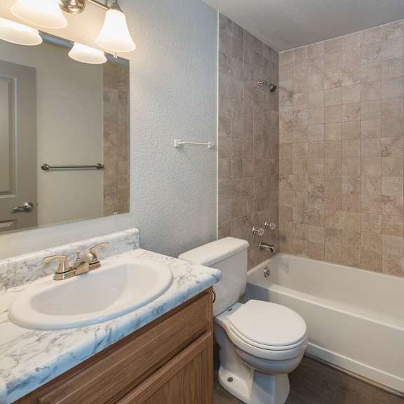 a bathroom with a marble countertop and a tiled shower.
