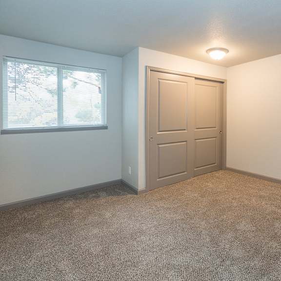 a room with a carpeted floor, a door, and a window.