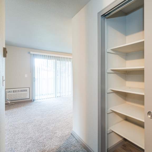 a white pantry with an open door revealing empty shelves.