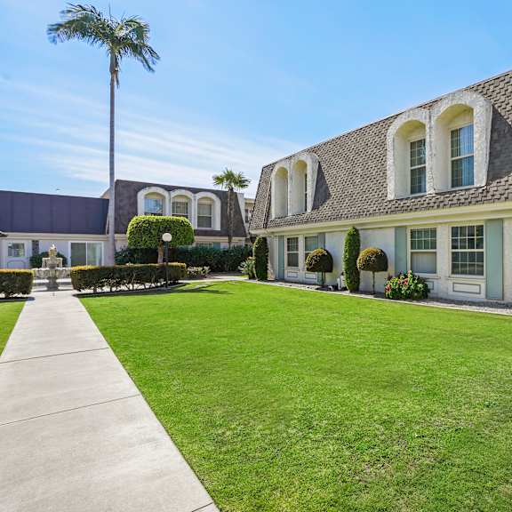 a house with a well-manicured lawn and a clear blue sky above.