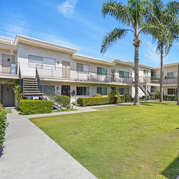 a sunny day at a residential complex with palm trees and well-maintained lawns.