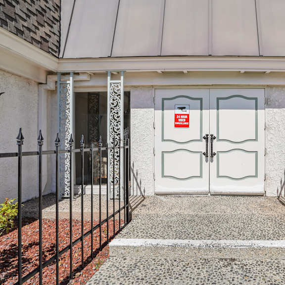 a white door with a red sign on it is flanked by two black metal fences.