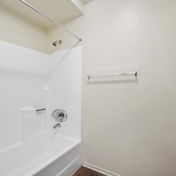 a white bathroom with a tub and towel rack.