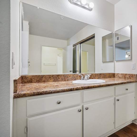 a bathroom with a sink, mirror, and cabinets.