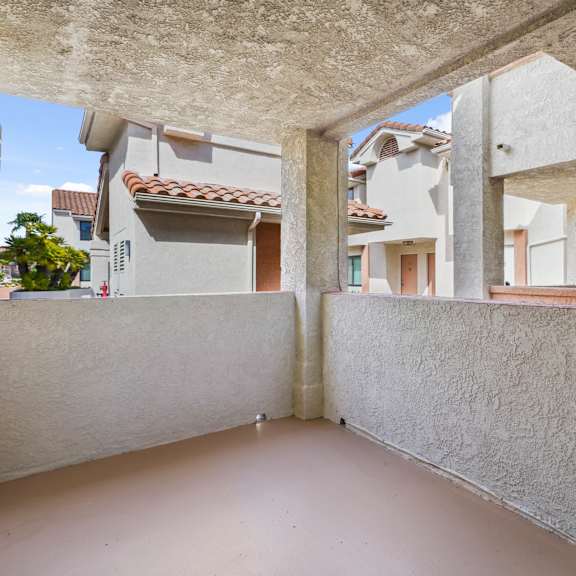 a balcony with a white wall and a building in the background.
