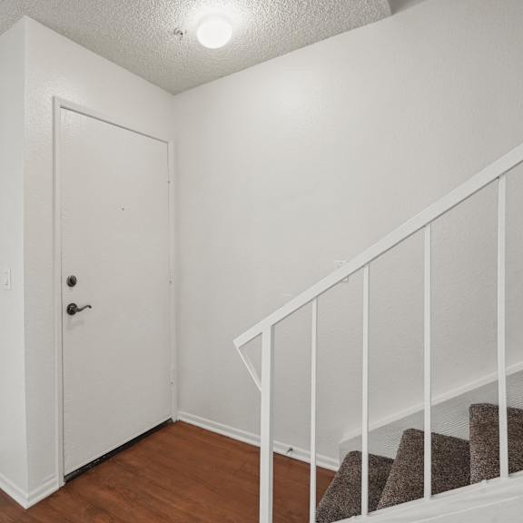 a white door is in a room with a staircase.