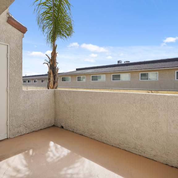 a balcony with a white door and a palm tree in the distance.