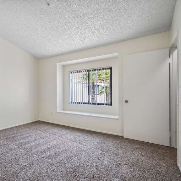 a room with a carpeted floor and a window with blinds.