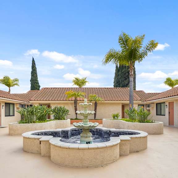 a courtyard with a fountain and palm trees.