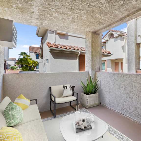 a patio with a white table and a chair with a yellow cushion.