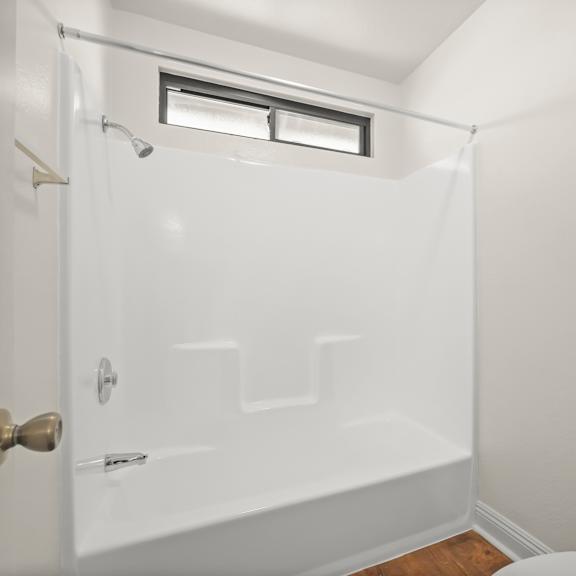 a white bathroom with a toilet, tub, and shower.