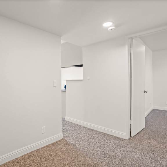 a white room with a carpeted floor and a door on the left.