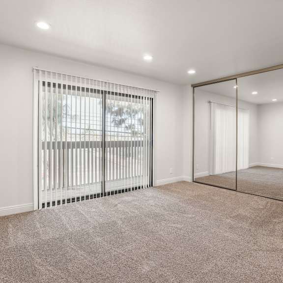 a room with a carpeted floor and a sliding glass door.