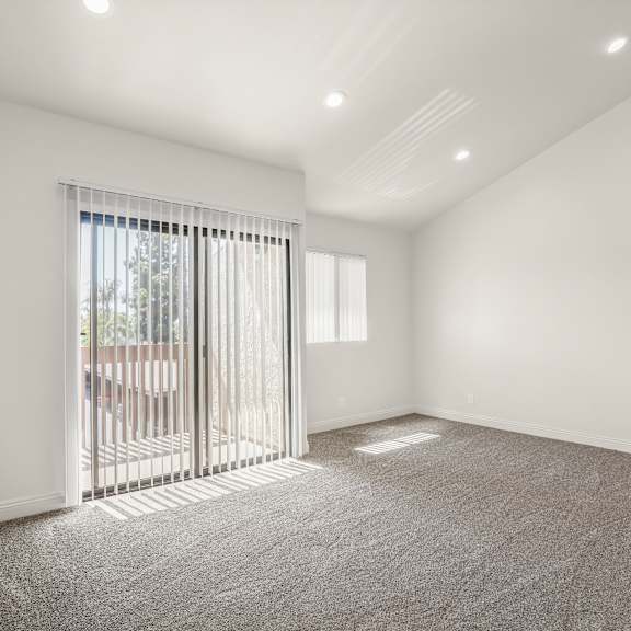 a room with a carpeted floor and a window with blinds.
