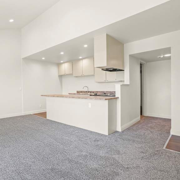 a spacious, empty room with a kitchenette in the corner.
