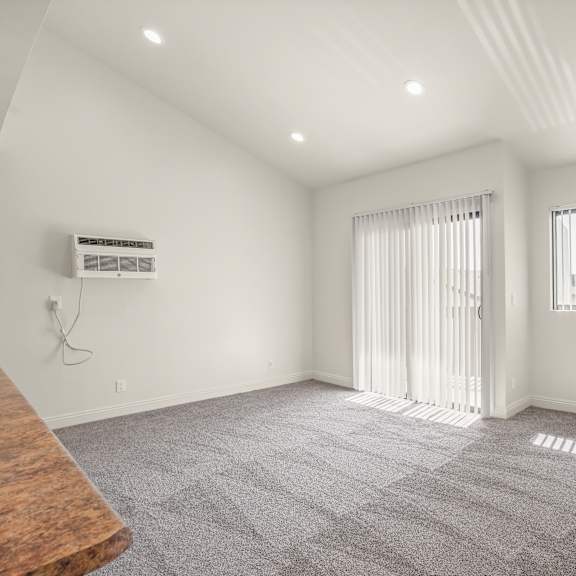 a spacious room with a carpeted floor and two windows with curtains.
