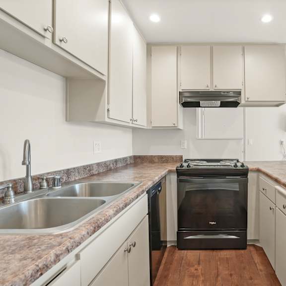 a kitchen with a stove, sink, and cabinets.