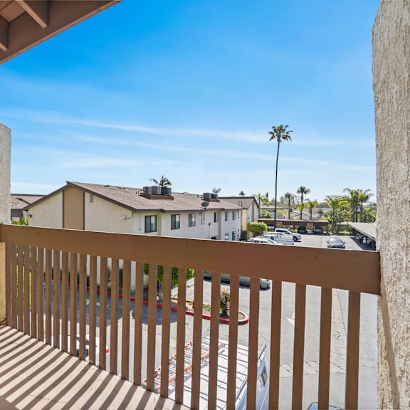 a balcony with a wooden railing overlooks a residential street.