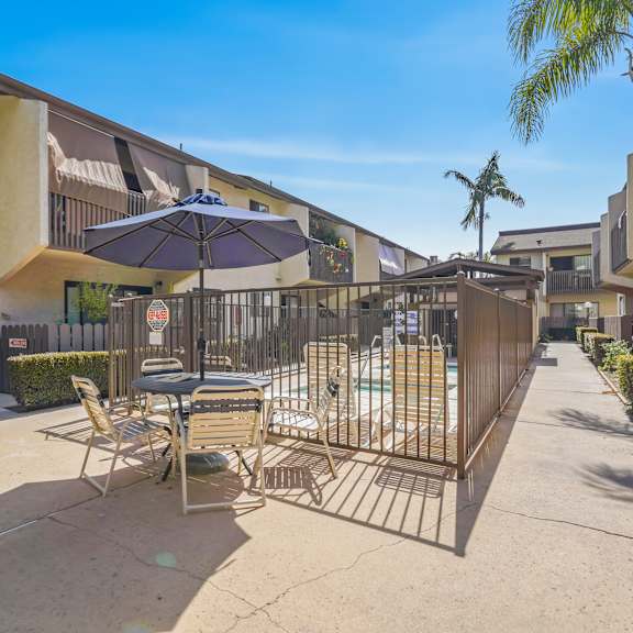 a patio with a table and chairs is surrounded by a metal fence.