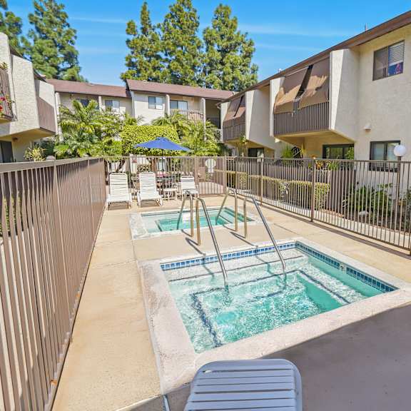 a pool with a slide in the middle of a patio surrounded by a fence.