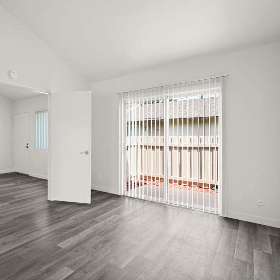 a room with white walls and a grey floor with a white door open.