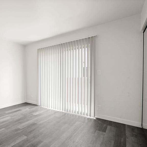a room with a window covered by vertical blinds.