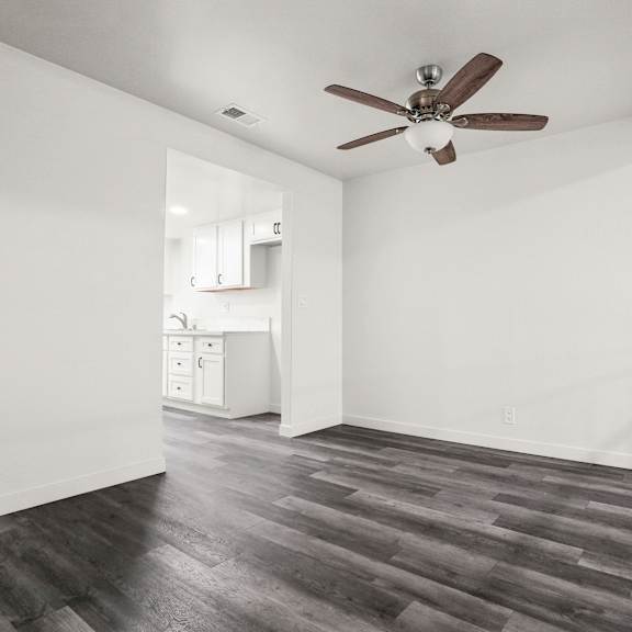 a room with a ceiling fan and wooden flooring.