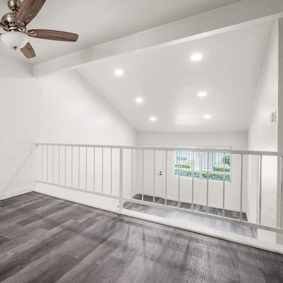 a room with a ceiling fan and wooden flooring.