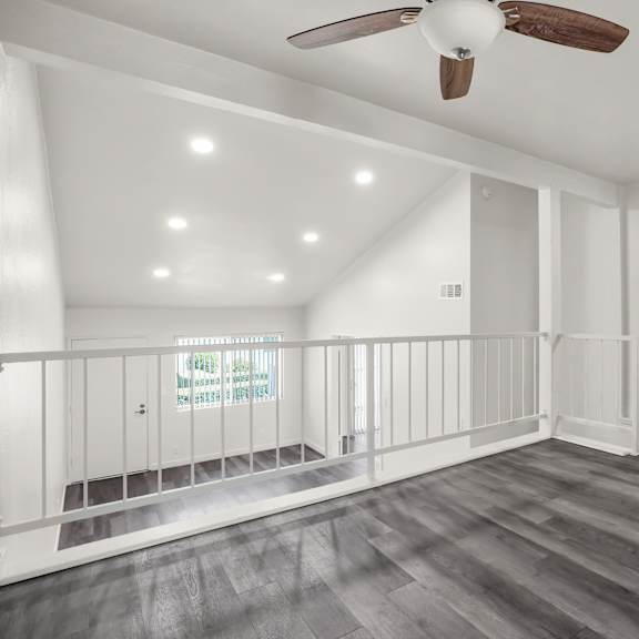 a spacious room with a ceiling fan and wooden flooring.