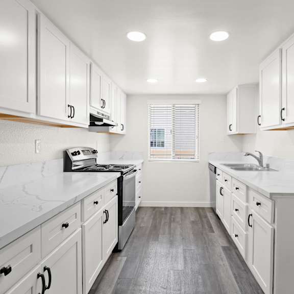 a kitchen with white cabinets and a marble countertop.