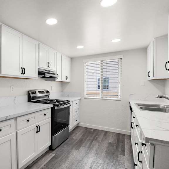 a kitchen with white cabinets and a marble countertop.