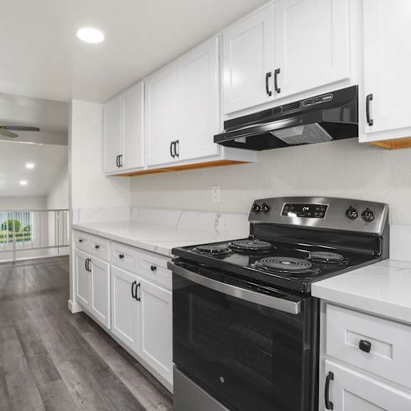 a modern kitchen with a black stove top oven and white cabinets.