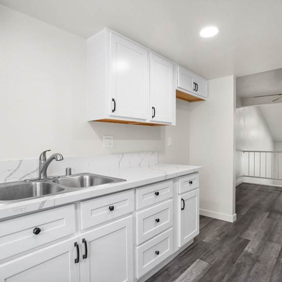 a kitchen with white cabinets and a stainless steel sink.
