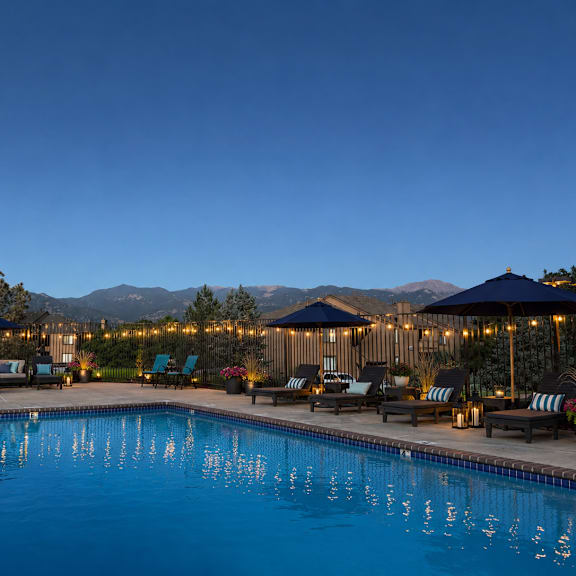 a large swimming pool surrounded by lounge chairs and umbrellas.