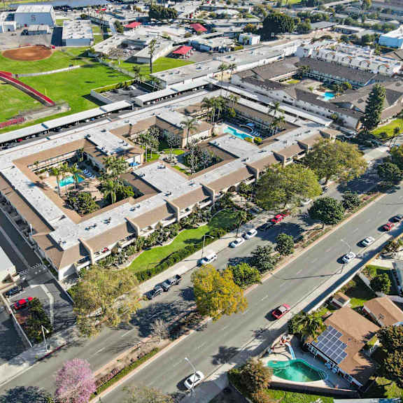 a baseball field is surrounded by buildings and a road.