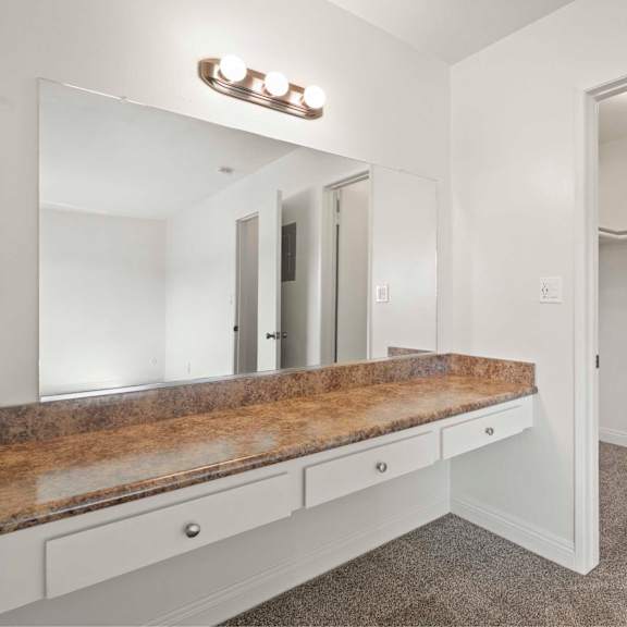 a white bathroom with a vanity and a mirror.